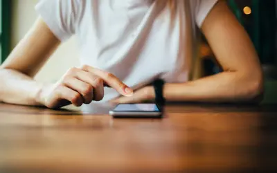 Dłoń dotyka ekranu smartfona, szukając informacji, jak zresetować telefon Redmi.