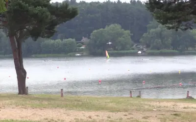 Pławniowice jezioro: wiatr napędza żaglówkę, a na brzegu widać piaszczystą plażę i drzewa.