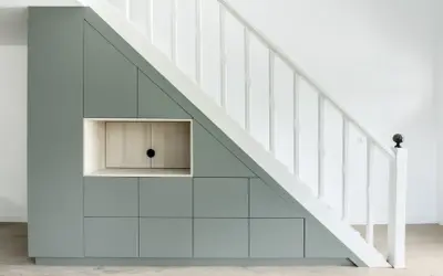 Aménagement sur mesure : un rangement sous escalier gris pâle avec des portes et une niche en bois clair.