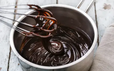 Fouet mélangeant du chocolat noir brillant dans une casserole, étape clé pour le tempérage.
