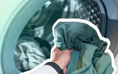 Hand lädt grüne Kleidung in eine Waschmaschine. Zeit, die neue Kleidung zu waschen und sie frisch zu machen.
