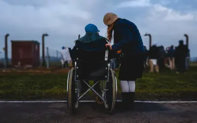 Donna assiste persona in sedia a rotelle, un momento di cura che ricorda l'importanza dell'indennità di accompagnamento dopo i 18 anni.