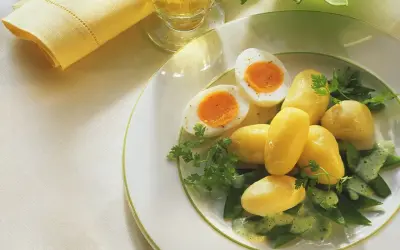 Ein einfaches zuckerschoten rezept: Salzkartoffeln, hartgekochte Eier und Zuckerschoten mit Kräutersauce auf einem Teller.