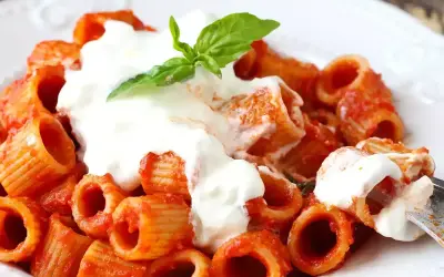 Rigatoni al sugo rosso con abbondante stracciatella cremosa e una fogliolina di basilico fresco.