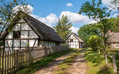 Tradycyjne chaty z drewnianą konstrukcją i strzechą, otoczone zielenią. Wspaniałe kluki atrakcje dla miłośników historii.