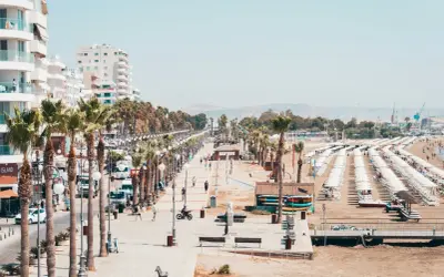 Promenada w Larnace z palmami, białymi budynkami i plażą pełną leżaków. Idealne miejsce, by zobaczyć, co oferuje Larnaka.