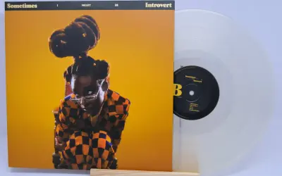 Little Simz, czasem introvert, na okładce płyty "Sometimes I Might Be Introvert". Obok przezroczysta winylowa płyta.
