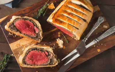 Un delicioso solomillo Wellington, jugoso y envuelto en hojaldre dorado, listo para ser cortado.