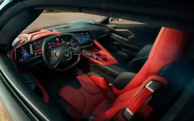 Wnętrze Chevrolet Corvette C8 z czerwono-czarnymi skórzanymi fotelami i nowoczesną deską rozdzielczą.