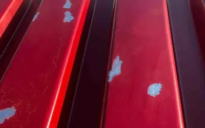 Detalles de la chapa galvanizada roja con pintura descascarada, mostrando el proceso de pintar chapa galvanizada.