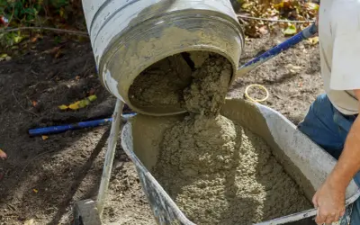 Betoniarka wylewa świeży beton do taczki. Zastanawiasz się, ile potrzeba cementu na kubik betonu?