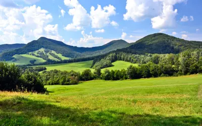 Zielone wzgórza i lasy Beskidu Niskiego pod błękitnym niebem z chmurami. Widok na malownicze **beskid niski szczyty**.