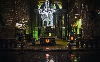 Wnętrze kaplicy w kopalniach soli w Wieliczce i Bochni. Kryształowy żyrandol oświetla ołtarz i kamienne rzeźby.