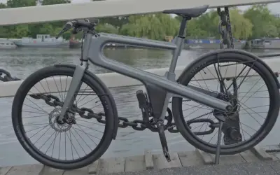 Moderne, hippe stadsfiets met een uniek frame, geparkeerd op een brug met uitzicht op boten.