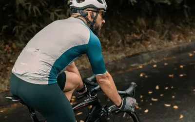 Ciclista con casco e occhiali pedala su strada bagnata, godendosi l'aria fresca. Un modo perfetto per alternare bici e camminata.