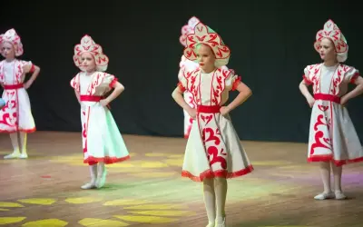 Niñas con trajes tradicionales bailan en un escenario de teatro.