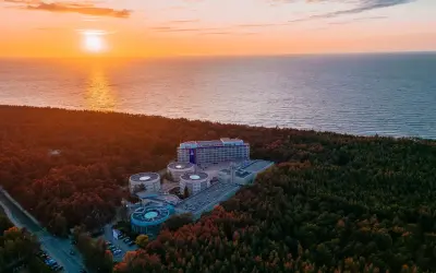 Zachód słońca nad morzem, otaczający las i kompleks hotelowy Hotel Senator Dźwirzyno.