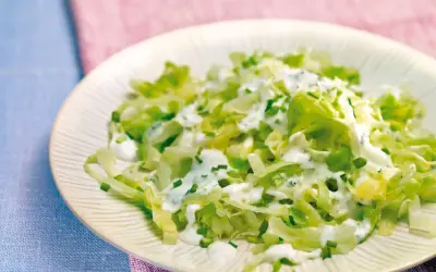 Frischer Spitzkohlsalat mit cremigem Dressing und Schnittlauch auf einem Teller.
