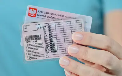 Dłoń trzyma polskie prawo jazdy z kategorią B, obok dowód osobisty.