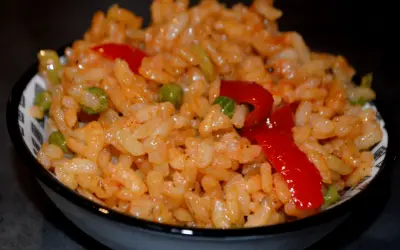 Un bol de riz coloré avec des petits pois et des poivrons rouges, parfait pour une recette salade riz facile et rapide.