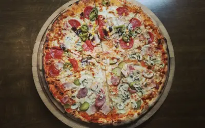 Pół na pół: pizza z salami i jalapeno oraz z szynką i pieczarkami. Zastanawiasz się, ile kalorii ma kawałek pizzy?