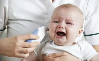 Płaczące dziecko z termometrem w uchu. Prawdopodobnie zapalenie ucha u dziecka.