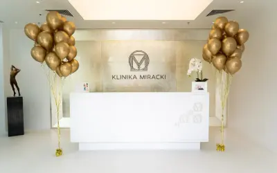Recepcja kliniki estetycznej z bukietami złotych balonów i rzeźbą.