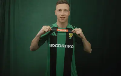 Młody piłkarz, którego miszor wiek sugeruje, że jest na początku kariery, prezentuje zielono-czarną koszulkę z logo Bogdanka.