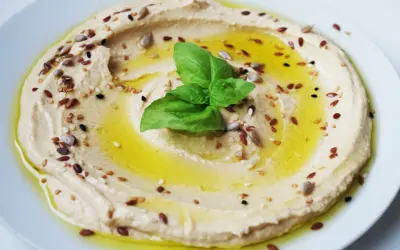 Cremiger Hummus, garniert mit Öl, Kräutern und Samen. Tahin ist die geheime Zutat für diese köstliche Dip-Kreation.