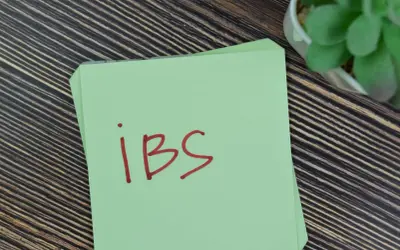 Zielona kartka z napisem "ibs" na drewnianym tle. Może to być przypomnienie o potrzebie leczenia, np. lekiem Duspatalin.