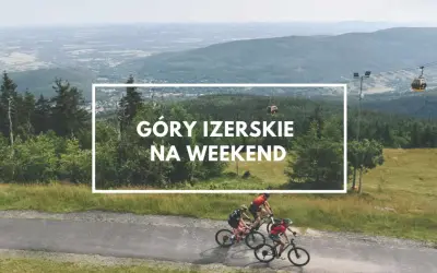 Góry Izerskie Polska: rowerzyści pędzą po górskiej drodze, w tle kolejka gondolowa i rozległy krajobraz.
