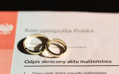Złote obrączki na odpisie skróconym aktu małżeństwa. Dokument potwierdza zawarcie związku, jak wygląda akt ślubu.
