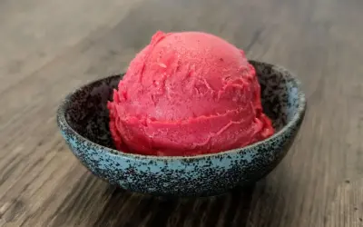 Ein Löffel Kirsch Eis in einer Schale auf Holztisch.