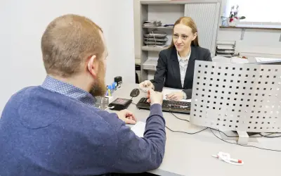 Mężczyzna przekazuje dokument do wymiany prawa jazdy urzędniczce.