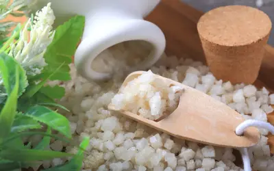 Magnesiumsulfat-Kristalle auf einem Holzlöffel, die die entspannende Wirkung von Magnesiumsulfat für ein wohltuendes Bad andeuten.