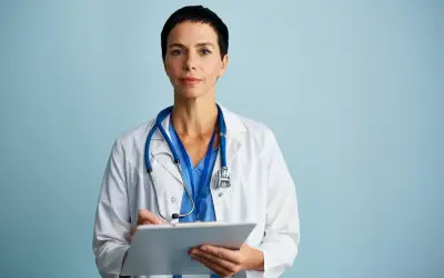 Medico con camice bianco e stetoscopio, appunti su cartella clinica. Ricerca sulla sindrome di Laron.