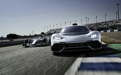 Wyścigowy bolid F1 i biały Mercedes-AMG Project One pędzą po torze.