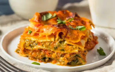 Pyszna lasagne wegetariańska z warzywami i sosem pomidorowym, udekorowana świeżą bazylią.