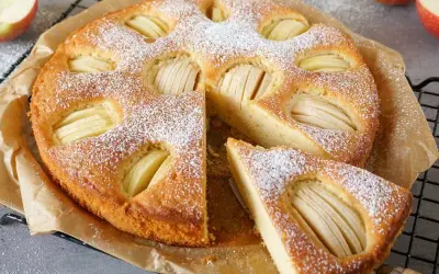 Omas weltbester Apfelkuchen, mit Puderzucker bestäubt und saftigen Apfelscheiben, wartet darauf, genossen zu werden.