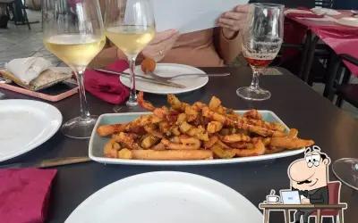 Tapas y copas de vino en el bar La Cala Almería. Un plato de patatas fritas con salchichas y una cerveza acompañan la comida.