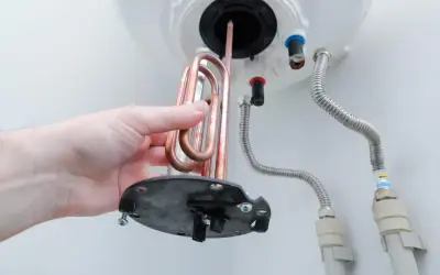 Mano retirando resistencia de cobre para saber como limpiar un termo por dentro.