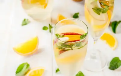 Verre de sangria blanche garni de tranches de pomme, d'orange et de menthe fraîche. Parfait pour une journée ensoleillée.