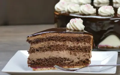Ein Stück saftige Schoko Sahne Torte mit glänzendem Schokoladenguss und zarter Sahnehaube.