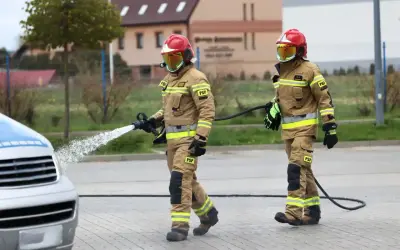 Strażacy w akcji, jeden z węża wodnego. Zastanawiasz się, ile zarabia strażak? To praca pełna poświęcenia.
