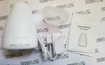 Un diffuseur d'arômes blanc, son adaptateur et son manuel. Un objet connecté pour une ambiance olfactive personnalisée.
