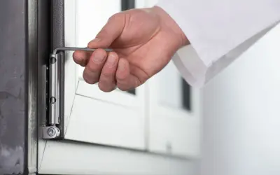 Dłoń reguluje okucie okna, gdy uchyla się i otwiera jednocześnie. Rozwiązanie problemu błędu okucia.