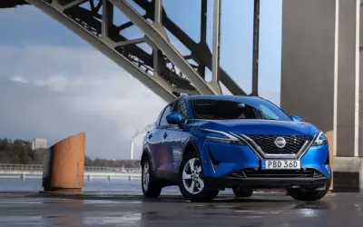 Blå Nissan Qashqai parkerad vid en bro. En spännande nissan qashqai test i en industriell miljö.