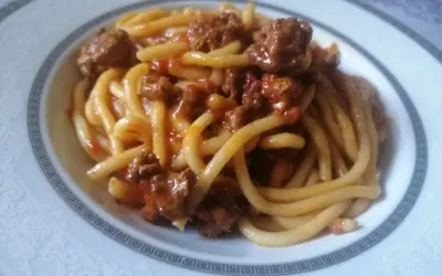 Pici fatti in casa conditi con un ricco ragù di carne, un classico della cucina toscana.