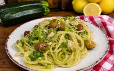 Un piatto invitante di pasta con zucchine e tonno, condita con olive e un tocco di limone.