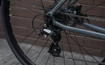 Tylna przerzutka Shimano Altus z widocznym hakiem do przerzutki, kasetą i łańcuchem na rowerze.